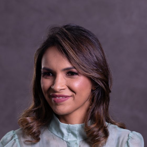 Arienny Mergulhão sorrindo, com blusa verde-água